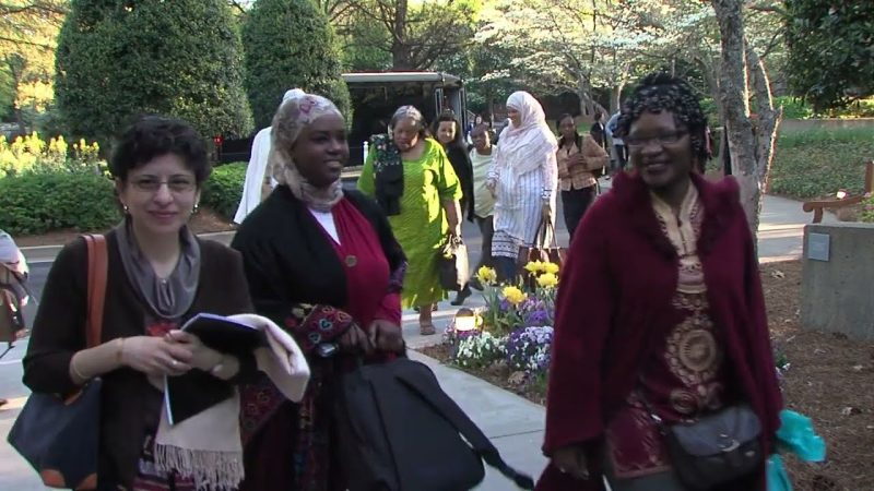 Three women walk toward the camera outside.